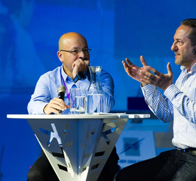 2 poeple sitting and talking on stage