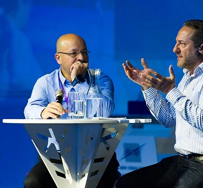 two people sitting and talking on stage